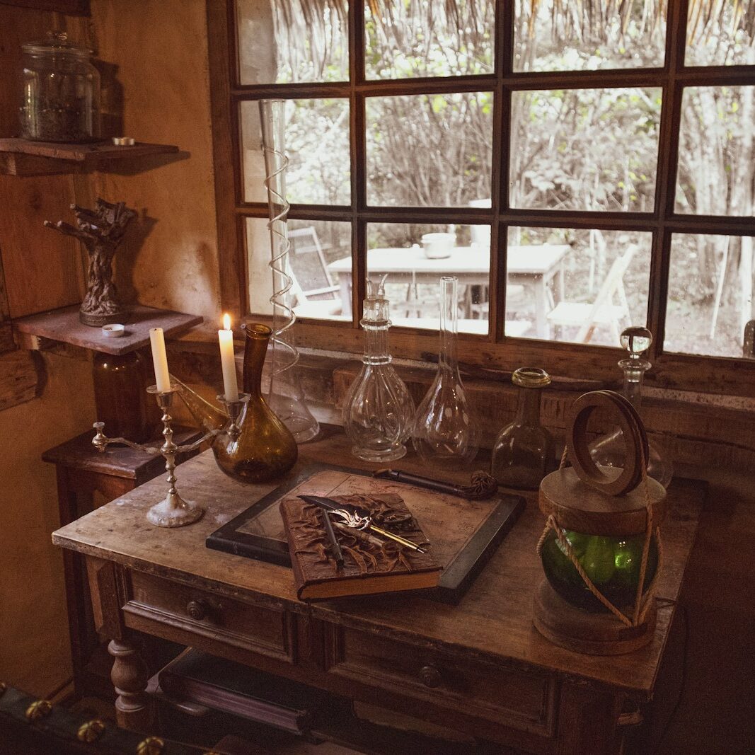 a wooden table topped with a bottle of wine next to a window